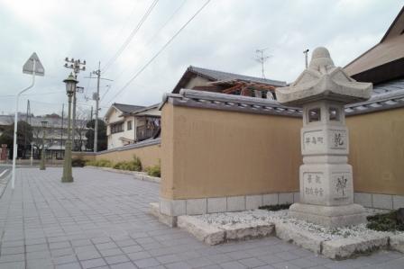 街路灯と石碑と一面に続いている小学校前の土塀の写真