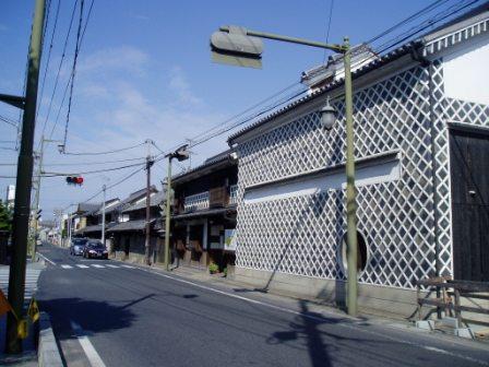 信号があるアスファルトの道路沿いに建つ金毘羅往来の町並みの写真