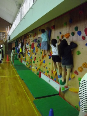 子供たちが壁に設置された突起につかまっているボルタリングの写真
