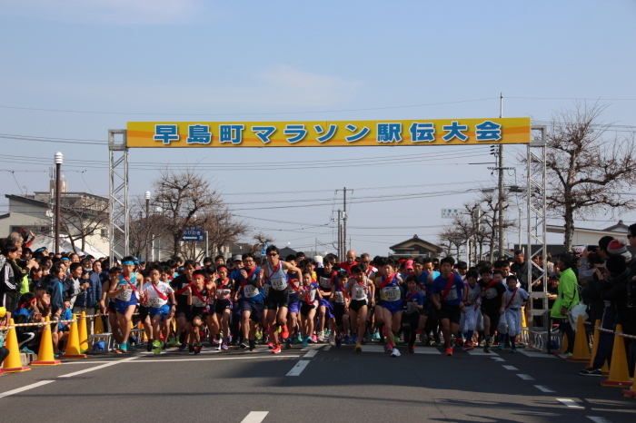 早島町マラソン駅伝大会の横断幕からスタートする大勢のランナーたちの写真