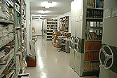 左右に灰色の書架が並んでいて本が保管されている写真
