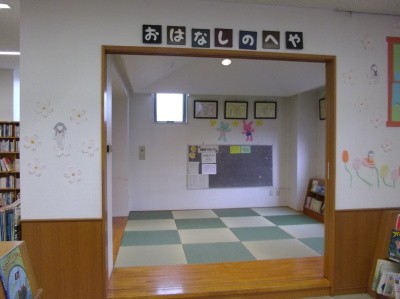 床に格子状の畳が敷いてある「おはなしのへや」と書かれた部屋の入口の写真