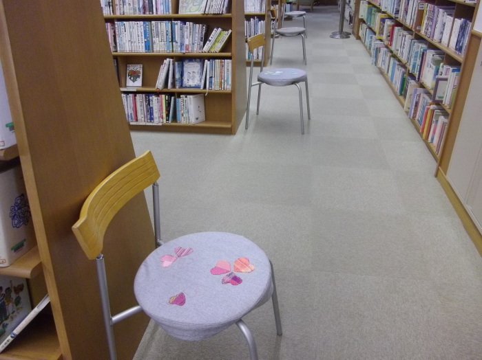 本棚がたくさん並べられている場所に丸い椅子が置かれていてハート模様の椅子カバー被されている写真