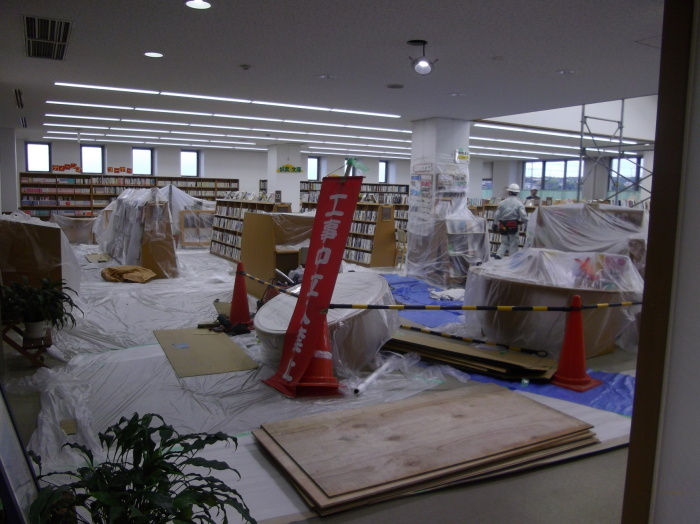 床や書架にビニールが掛けられ「工事中立入禁止」と書かれた幕が立てられている工事中の図書館の様子の写真