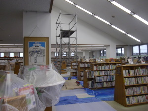 カウンターにビニールが掛けられて床に青い養生シートが敷かれているリニューアル中の図書館の様子の写真