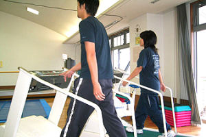 Tシャツにジャージのズボンの二人の男女が歩行マシンで運動をしている写真