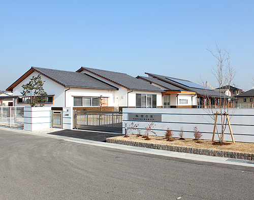 白いブロック塀と白を基調にした建物の地域活動支援センター「栴檀の家」の写真
