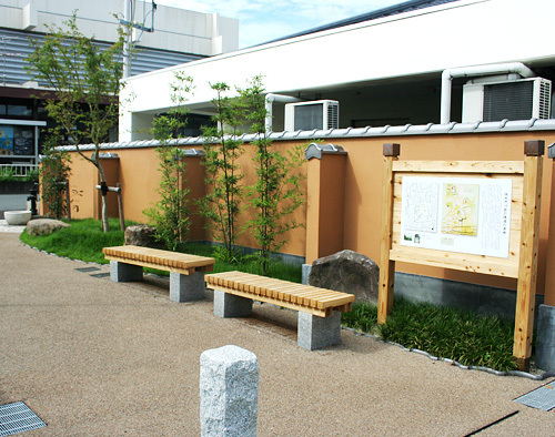 木製の掲示板とベンチが設置されている広場の写真