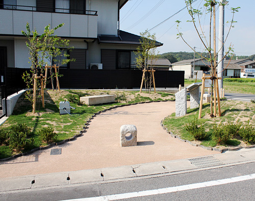 石でできたベンチと芝生に木が植えられている広場の写真