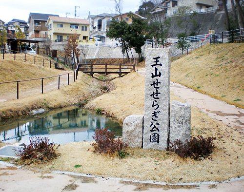 小さな川が流れている公園と王山せせらぎ公園と記された記念碑の写真
