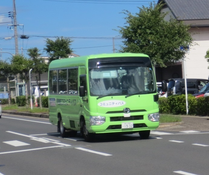 黄緑色の小さなコミュニティバスが道路を走行している写真