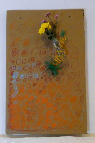 茶色い板に丸い模様が描かれていて針金で花をぐるぐる巻きにしている写真