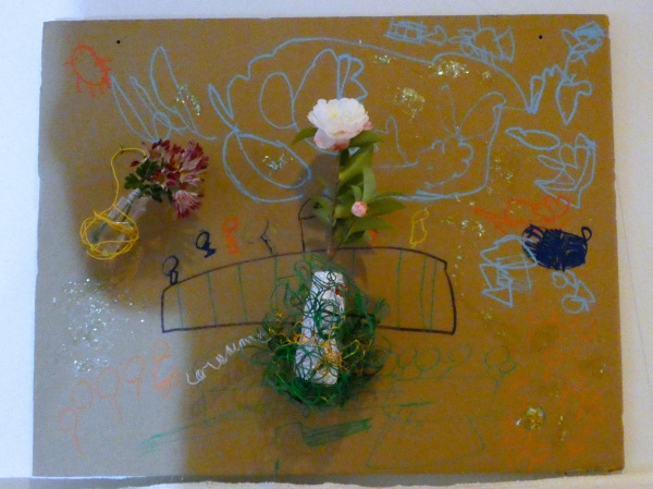 茶色い板に模様が描かれていて針金を使って3つの花が巻き上げられている写真