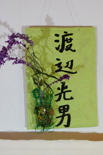 緑色の布に渡辺光男と書かれた脇に花が糸でぐるぐる巻きにされている写真