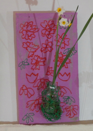 ピンクの布に花の模様が描かれていて水仙の花が緑色の糸でぐるぐる巻きにされている写真